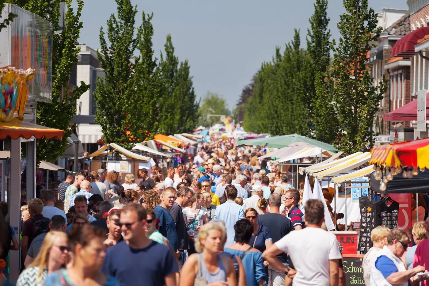 Een drukke straat vol kramen en bezoekers tijdens de paardenmarkt